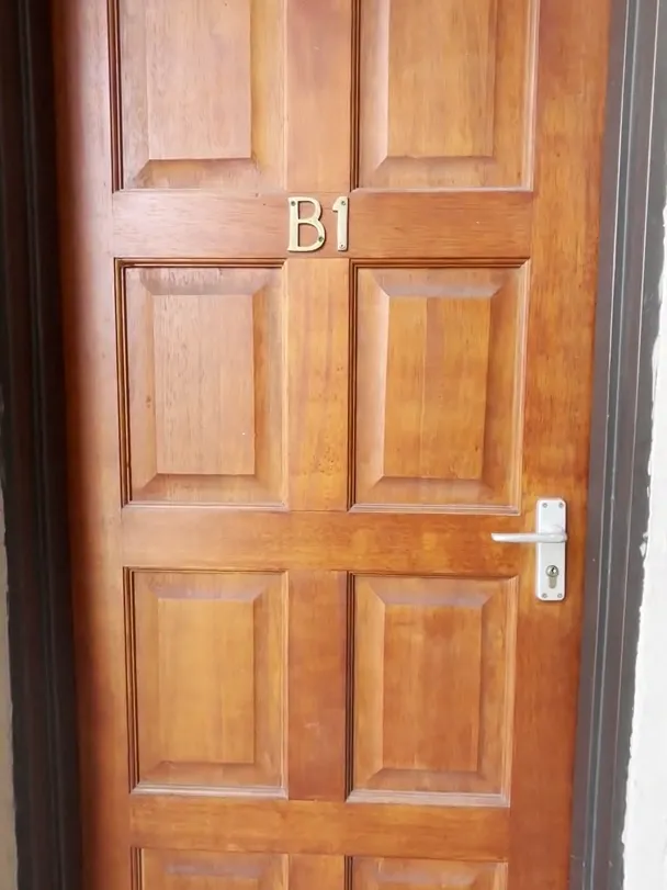 Wooden panelled front door with a metal handle and the number B1 on it