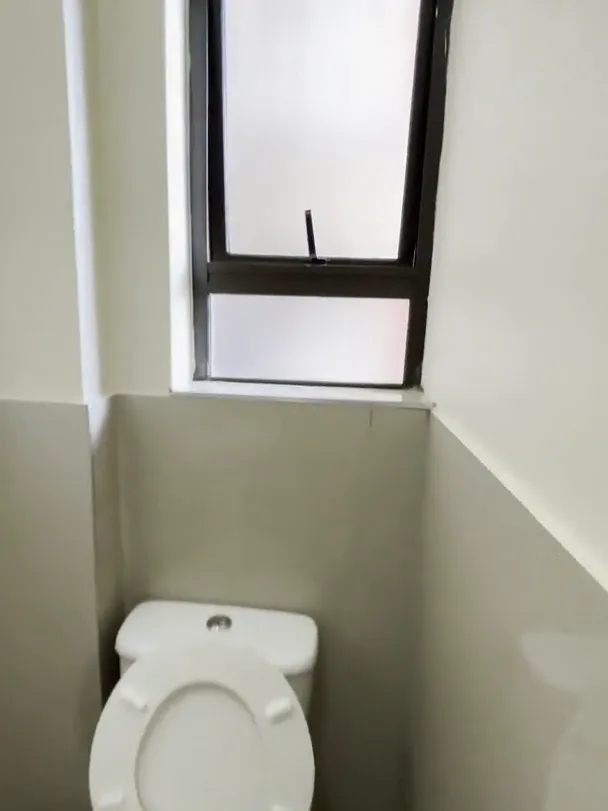 Toilet with the seat lifted, a half-tiled wall and a small frosted window above it