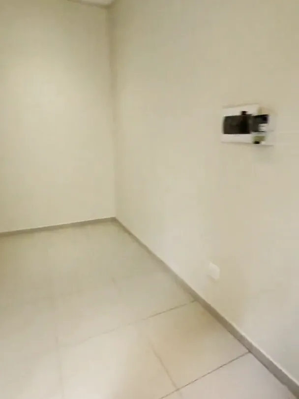 Empty room with a light tiled floor, cream walls and a small electrical box on one wall